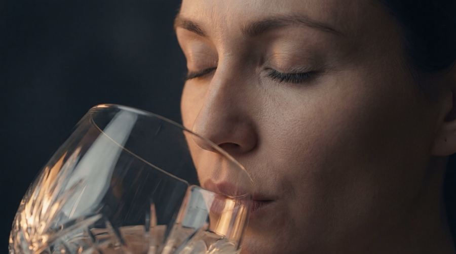 Eine Frau riecht mit geschlossenen Augen an einem Kristallglas mit Nord Gin